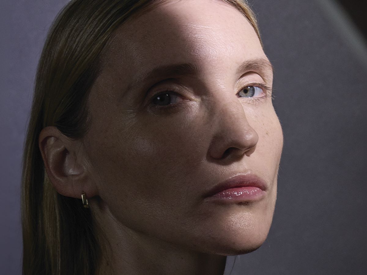 model with glowing skin looking at the camera on a grey background