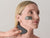woman using a gua sha and a charcoal mask